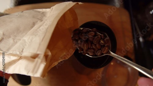 Top down shot of a man scooping coffee beans into a coffee grinder