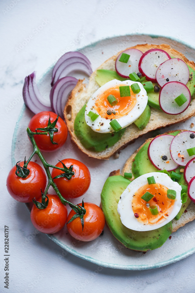 Healthy breakfast, Toasts with avocado, egg, radish, sweet onions and tomatoes, Diet food, On a light marble background, Selective focus closeup