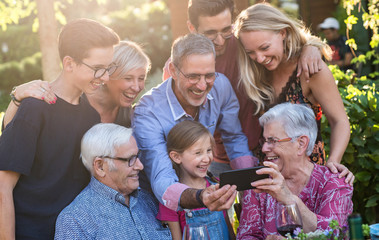  During a bbq, the family have fun sharing a video on a phone
