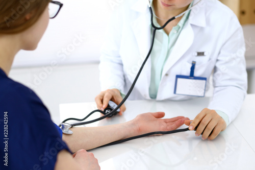 Doctor woman checking blood pressure of female patient, close-up. Cardiology in medicine and health care concept