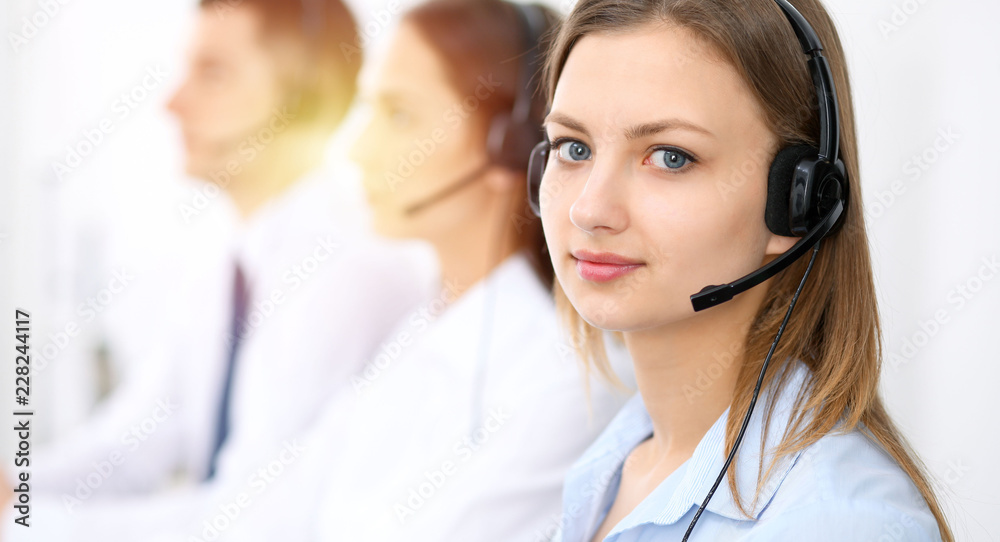 Call center operators. Focus on young cheerful smiling woman in headset. Business and customer service concepts Call center operators. Focus on young cheerful smiling woman in headset. Business and customer service concepts