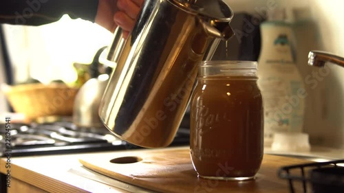 Man pours coffee out of a french press into a mason jar inside an airstream