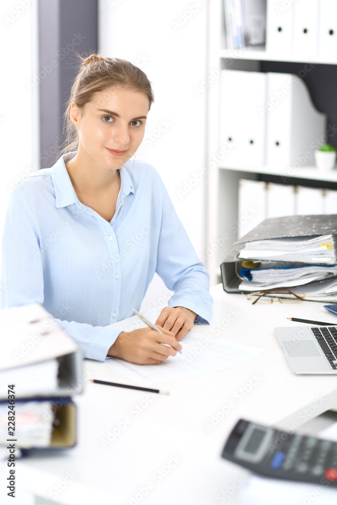 Woman bookkeeper or financial inspector calculating or checking balance, making report. Internal Revenue Service at work with financial document. Tax and audit concept Woman bookkeeper or financial inspector calculating or checking balance, making report. Internal Revenue Service at work with financial document. Tax and audit concept