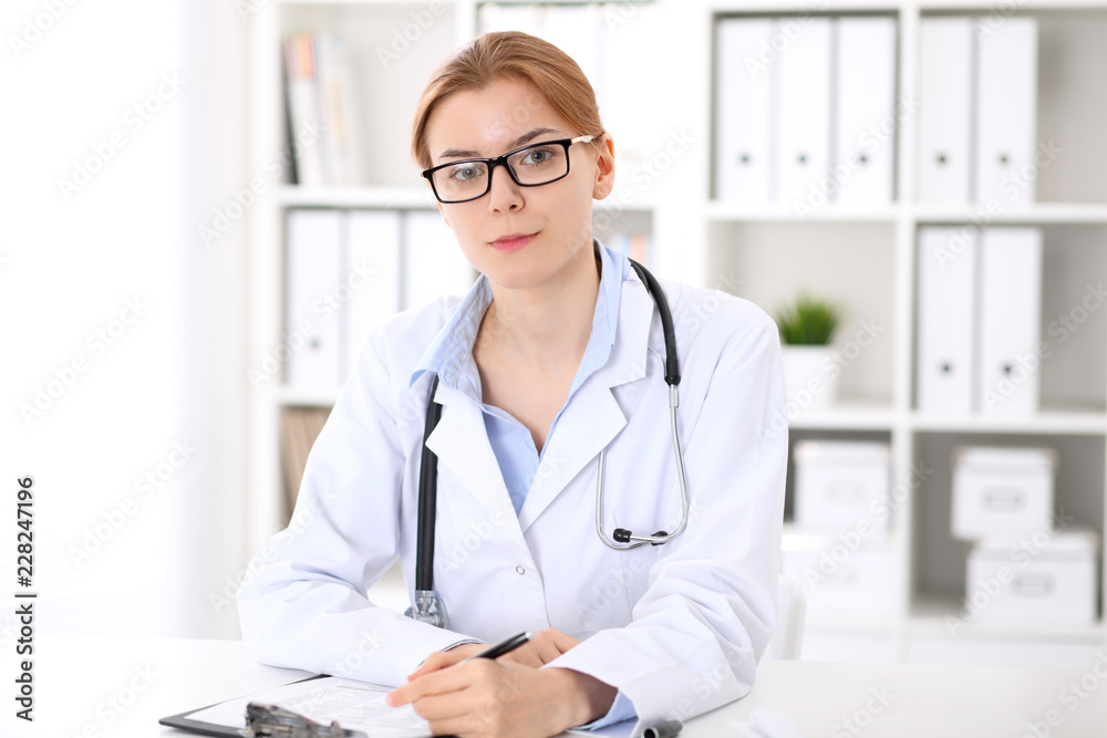 Young brunette female doctor at work in hospital. Physician ready to help. Medicine and healthcare concept Young brunette female doctor at work in hospital. Physician ready to help. Medicine and healthcare concept