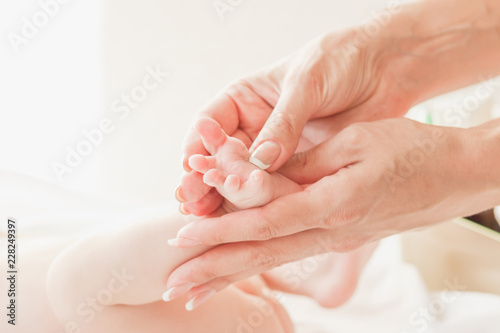Hands of woman and baby foot, soft focus background