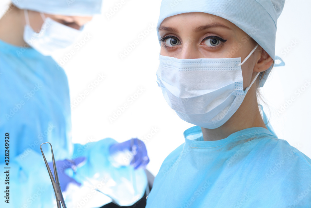 Surgeon doctor in mask performing operation. Focus on female intern girl. Medicine, emergency help concepts Surgeon doctor in mask performing operation. Focus on female intern girl. Medicine, emergency help concepts