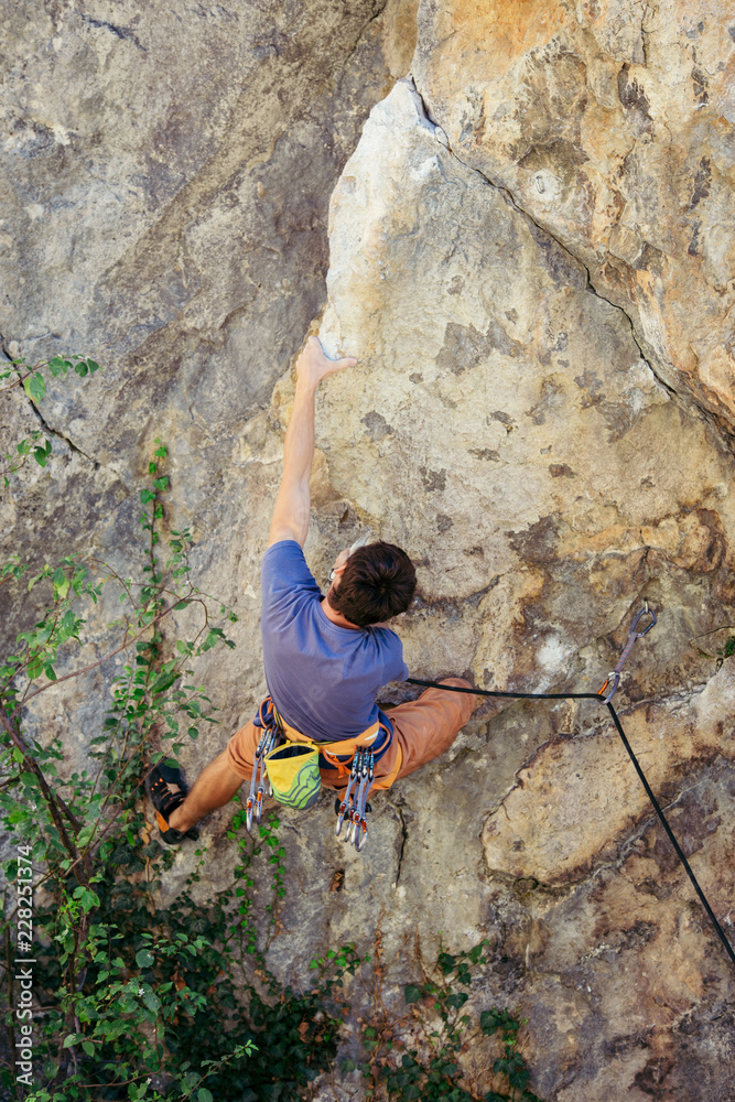 Young man climbs the yellow rock, hard route 7c, lead.