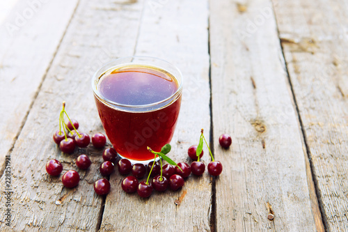 Homemade cherry juice in glass with freshcherry on wooden table. Fresh fruit drink photo