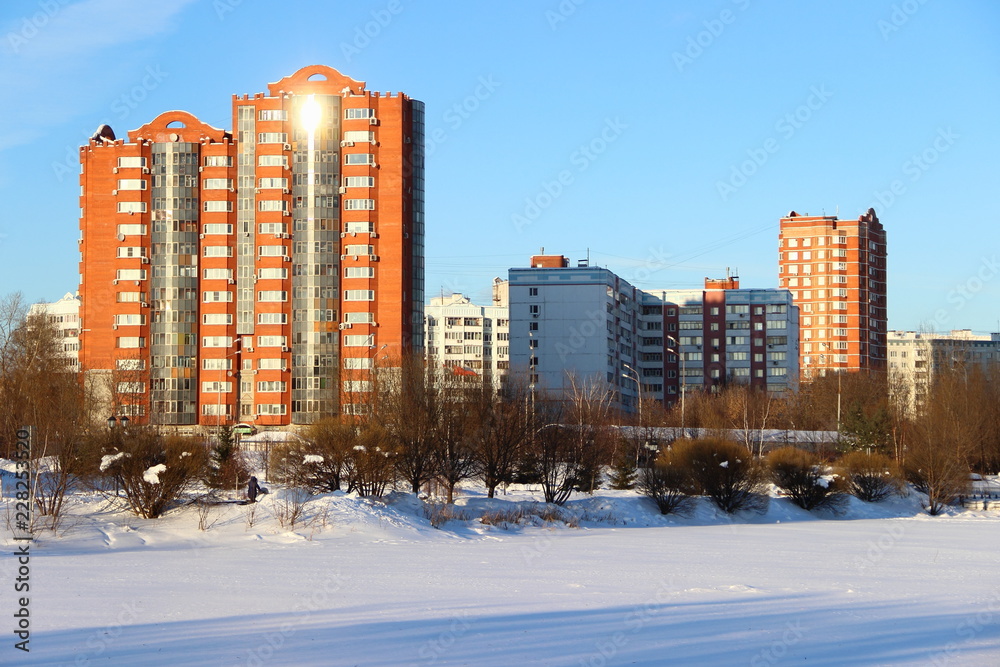 Obraz premium Russia, Moscow region, Mytishchi. Beautiful winter in the city Park - frozen lake under the snow on the background of modern high-rise buildings and blue clear sky on a sunny winter day