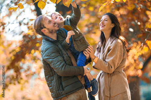 Young family having fun in the autumn park with his son.