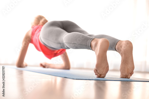 Fototapeta Naklejka Na Ścianę i Meble -  Young woman practicing yoga indoors