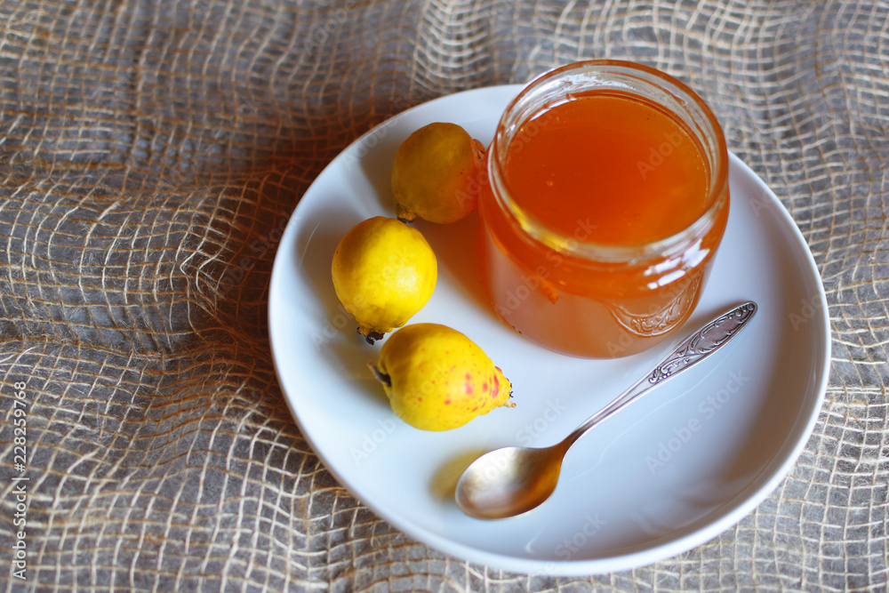 Honey in glass jar spoon and three fresh yellow quince fruits on white plate on linen cloth background. Honey in glass jar spoon and three fresh yellow quince fruits on white plate on linen cloth background.