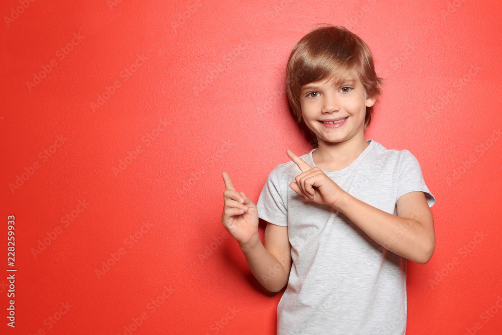 Little boy in t-shirt pointing at something on color background Little boy in t-shirt pointing at something on color background