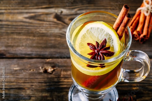 Photos Hot spiced Apple cider Toddy with lemon, honey and cinnamon stick in glass on wo