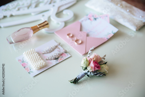 Brides set of wedding accessories  perfume and earrings on the table with flowers background. Concept of jewellery.