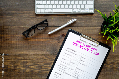 Social security. Disability claim form near glasses on dark wooden background top view space for text photo