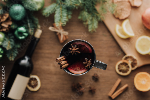 top view of cup of homemade mulled wine with cinnamon sticks on wooden tabletop, christmas concept