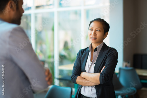 Konstfotografi Serious Asian woman with crossed arms looking at male partner