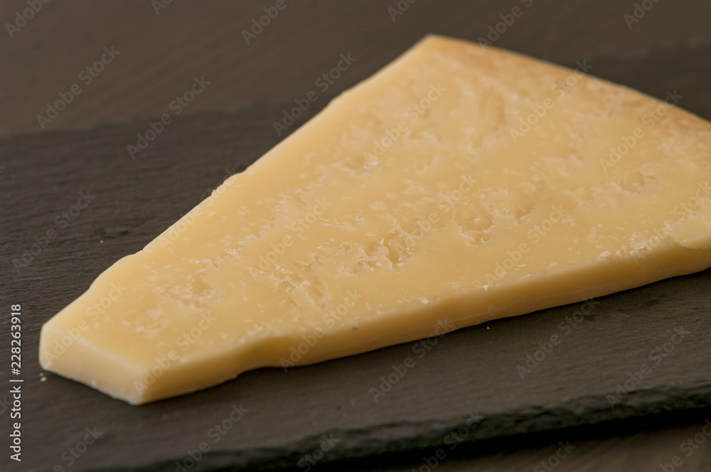 Slice of cheese on black slate board, close-up Slice of cheese on black slate board, close-up