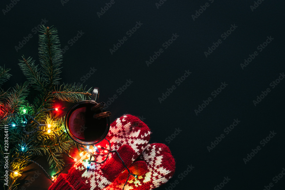 top view of cup of mulled wine, garland and mittens isolated on black, christmas concept