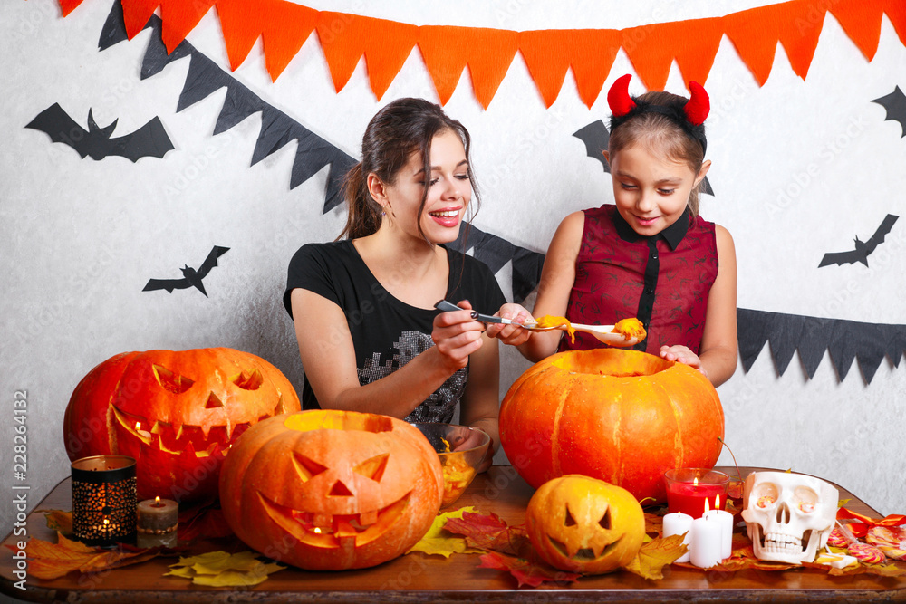 Fototapeta premium Happy Halloween! Mother and daughter carving pumpkin. Family preparing for holiday.