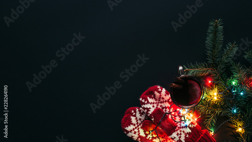 elevated view of cup of mulled wine, garland and mittens isolated on black, christmas concept