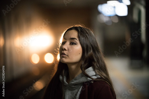 Portrait of young woman in subway. Night. The train arrives
