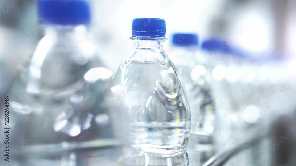 Clean water in plastic bottle moves through conveyor factory.