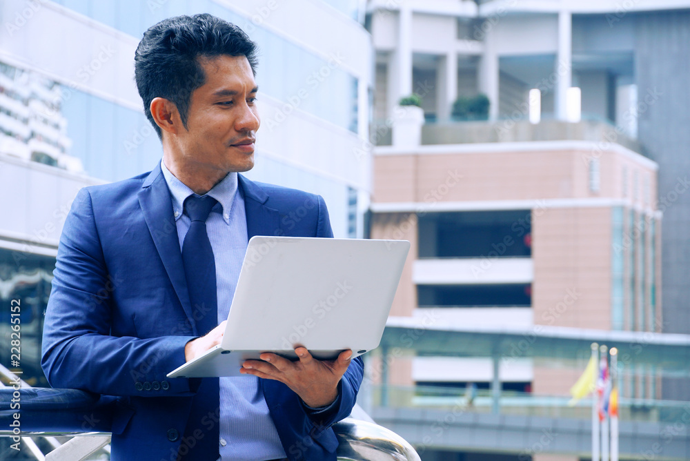 Fototapeta premium Asian businessman carry notebooks stand outdoor and act thinking,have space for idea.