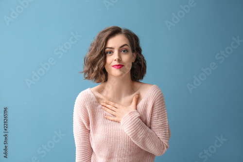 Portrait of beautiful flattered woman on color background photo