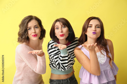 Portrait of beautiful women blowing kisses on color background