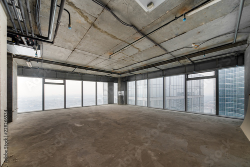 Perspective view of empty cement floor and ceiling interior with city skyline view