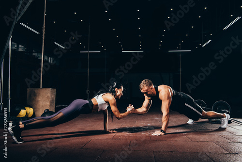 Panel kuchenny z motywem athletic sportsman and sportswoman doing push ups together and holding hands in dark gym
