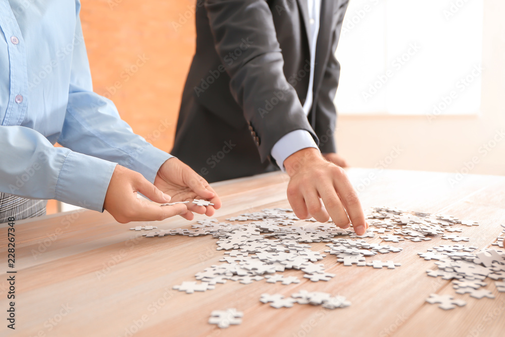 Business team assembling puzzle on wooden table Business team assembling puzzle on wooden table