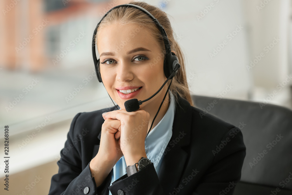 Beautiful female secretary talking through headset in office Beautiful female secretary talking through headset in office