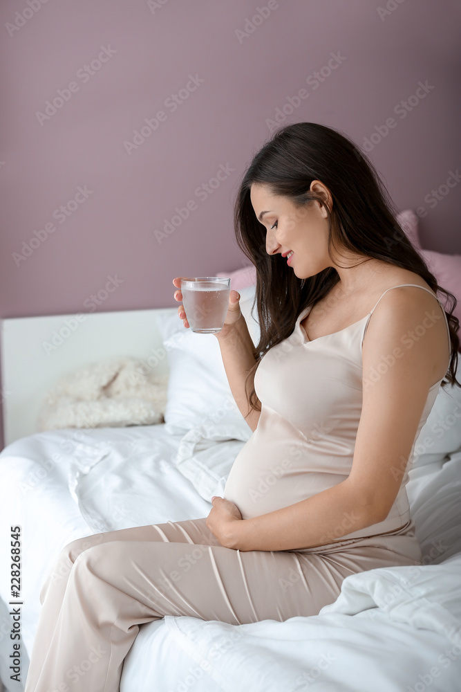 Beautiful pregnant woman drinking water in bedroom Beautiful pregnant woman drinking water in bedroom