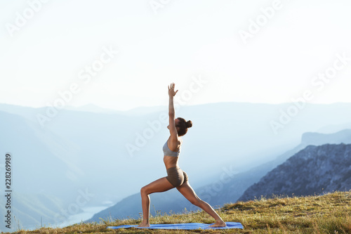Girl practicing yoga on top of the mountain