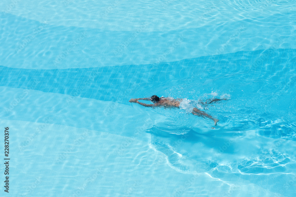 Aerial  view on the men in the swimming pool with transparent blue water. In the motion