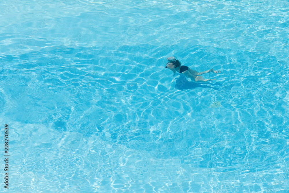 Aerial top view on the swimming woman in the swimming pool with transparent blue water. in motion