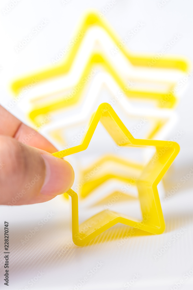 Hand holding star shaped pastry cutter on a white background Hand holding star shaped pastry cutter on a white background