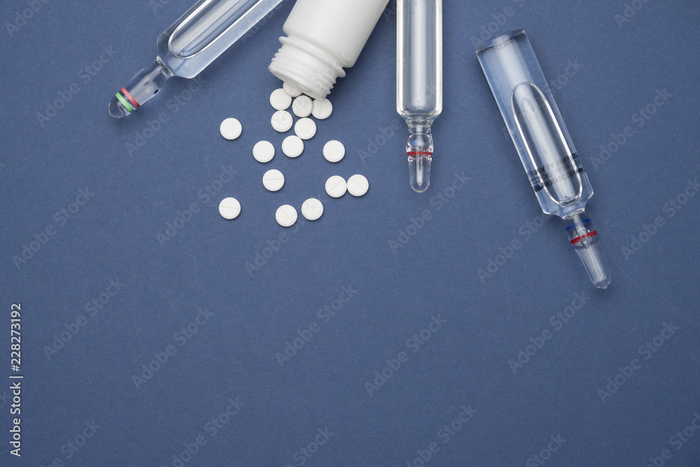 Naklejka premium Some vials next to pills white isolated in blue background