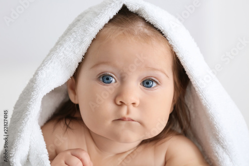Cute little baby with soft towel on light background