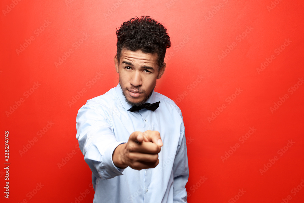 Portrait of African-American man pointing at viewer on color background Portrait of African-American man pointing at viewer on color background