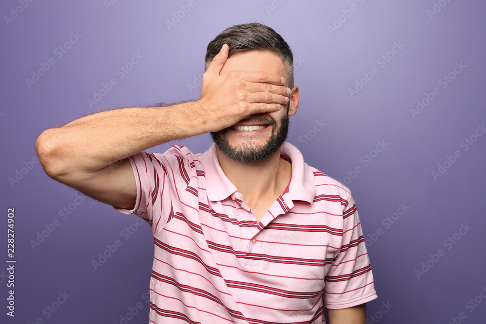 Portrait of man covering eyes with hand on color background Portrait of man covering eyes with hand on color background