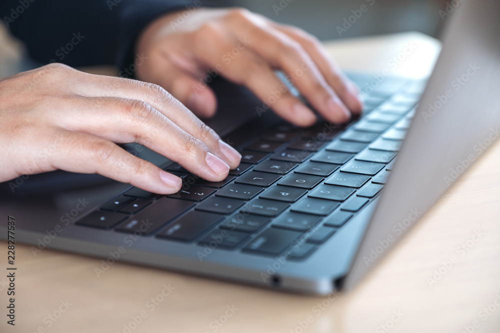 Closeup image of hands using and typing on laptop keyboard on table Closeup image of hands using and typing on laptop keyboard on table