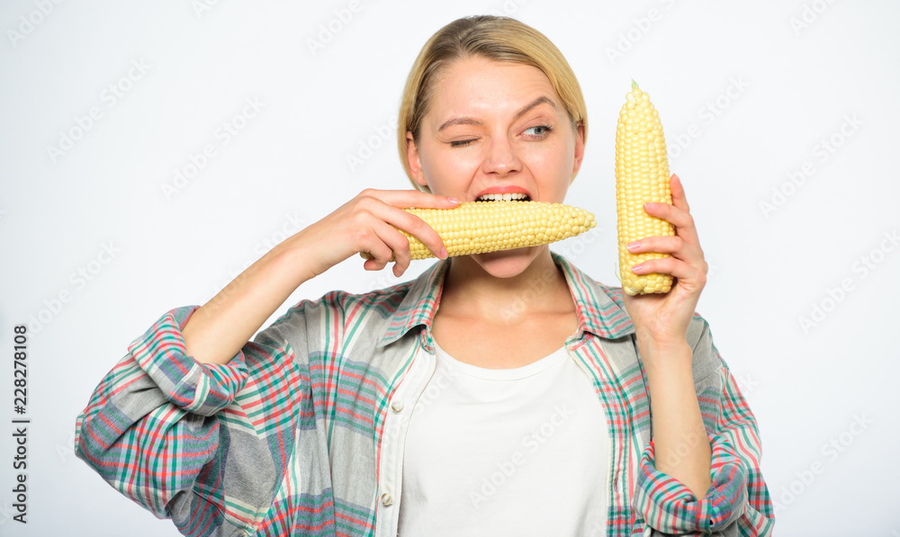 Vegetarian product. Raw food diet concept. Girl practice eating only or mostly food uncooked and unprocessed. Woman farmer bite yellow corn cob on white background. Girl rustic style hold ripe corn Vegetarian product. Raw food diet concept. Girl practice eating only or mostly food uncooked and unprocessed. Woman farmer bite yellow corn cob on white background. Girl rustic style hold ripe corn