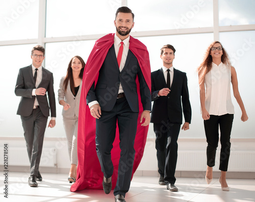 businessman is a superhero, stepping ahead of his business team photo