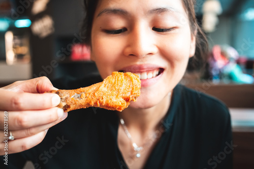 Young woman tasted fried chicken drumstick