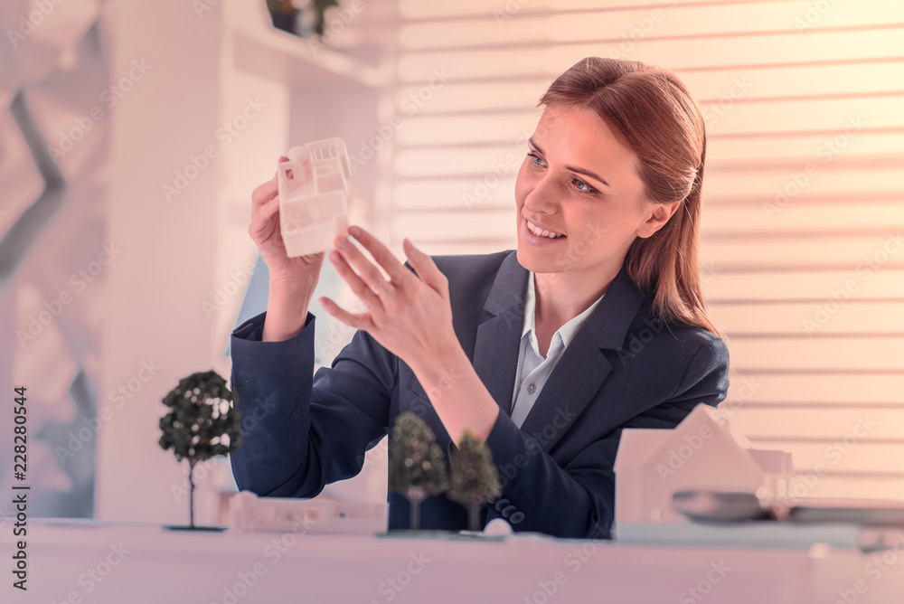 Formal style. Cheerful female person keeping smile on her face while sitting at her workplace Formal style. Cheerful female person keeping smile on her face while sitting at her workplace