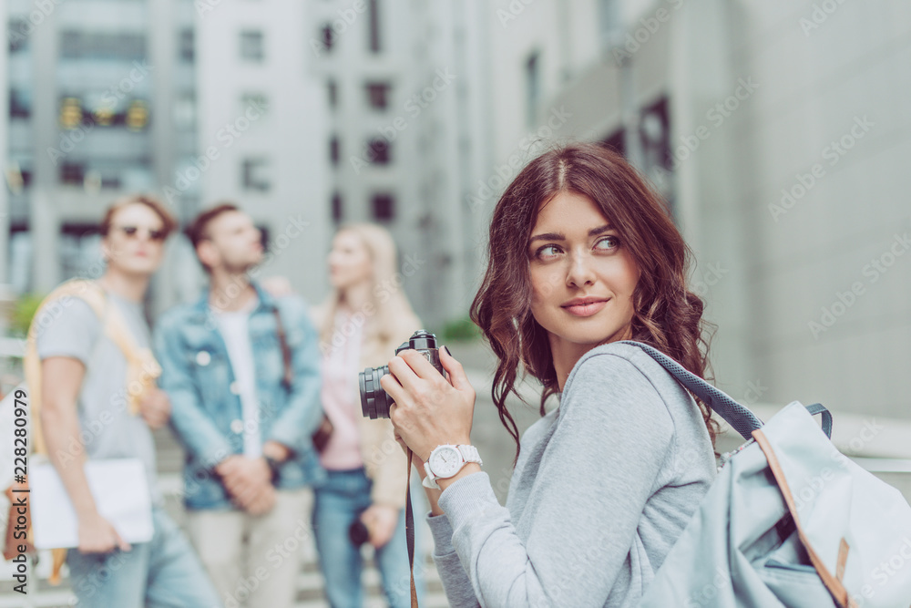 beautiful female photographer with camera in city with friends